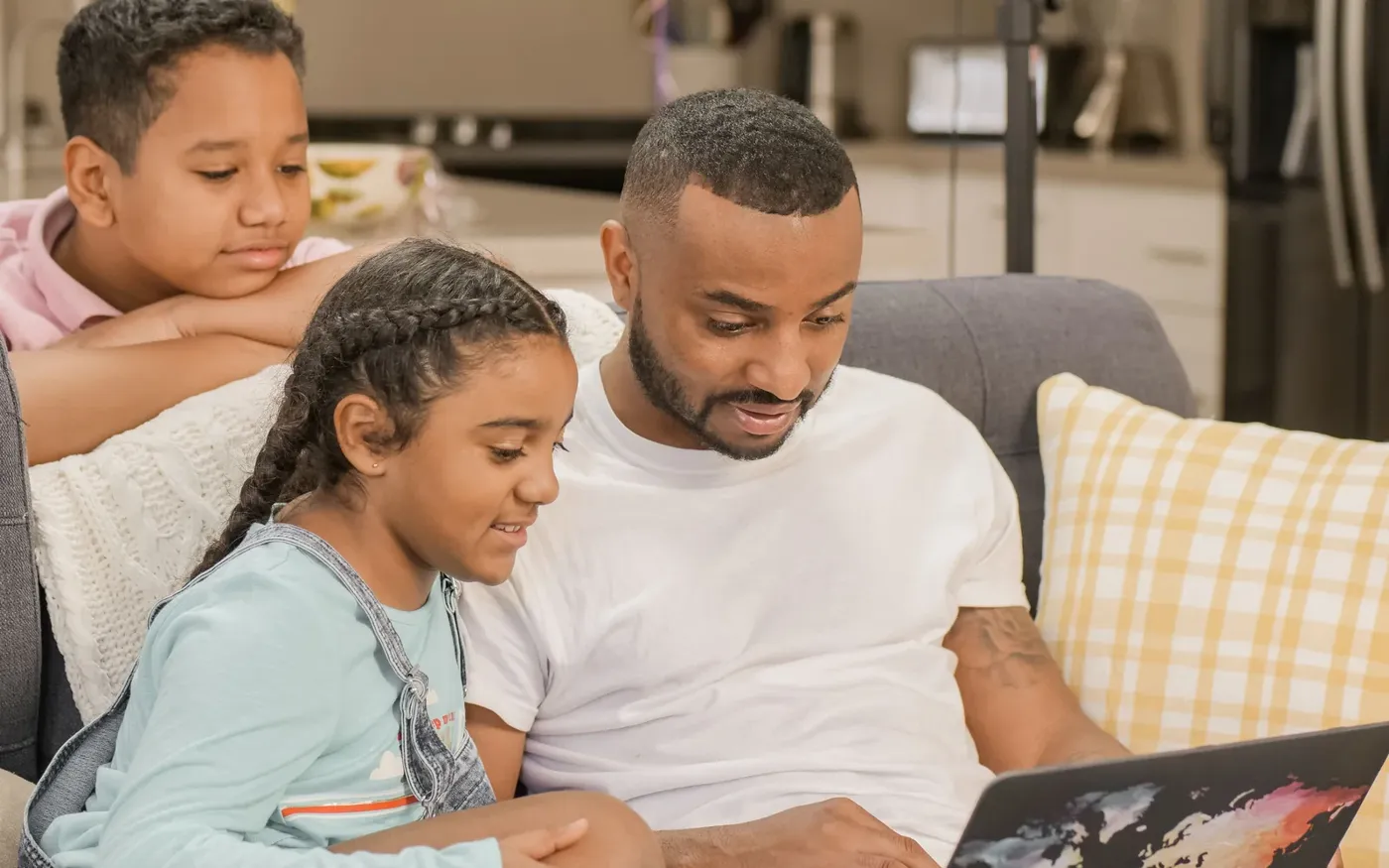 Father and two children reviewing a term life quote on a laptop at home